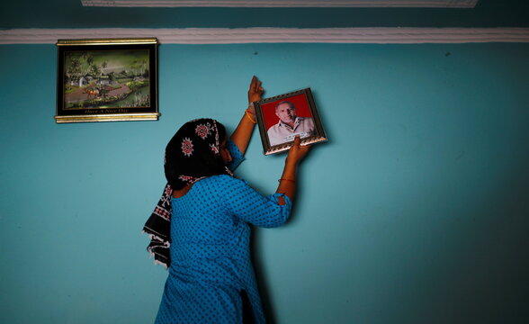 Daughter-in law of Balraj Singh, a teacher who died from the coronavirus disease (COVID-19) after he attended his local election duty in April, hangs his photo on the wall inside their house at Astoli village