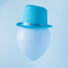 A blue balloon with a hat on it. Party concept. Minimal composition.
