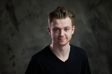 Obraz premium High resolution photo portrait of a cute caucasian guy in a studio on a gray background with a smile