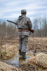 a hunter is waiting for a woodcock in the evening in the spring forest