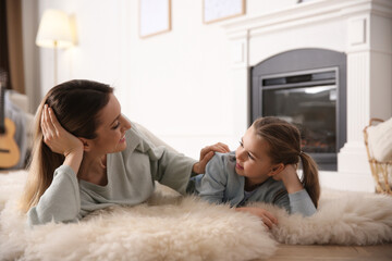 Happy woman with her daughter resting near fireplace at home