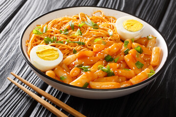 Rabokki street food is tteokbokki with ramen noodles in a spicy sauce close-up in a bowl on the table. horizontal