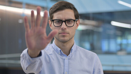 Portrait of Young Man showing Stop Sign by Hand