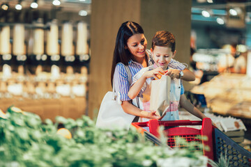 Mother and son buying fruit at grocery store or supermarket - shopping, food, sale, consumerism