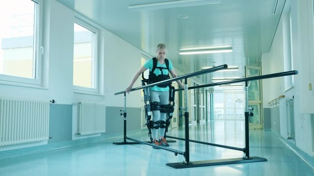 Young woman is training walking while wearing exoskeleton