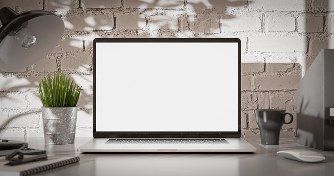 Laptop blank screen in a loft industrial office interior with brick wall