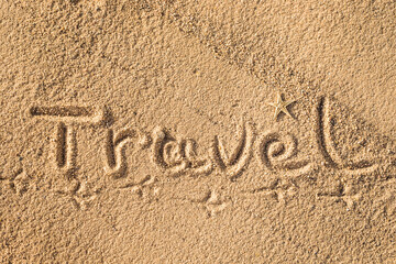 Word Travel written in the sand on the beach.  Summer travel concept. Birds footprints on yellow sand.
