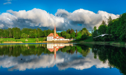 Fototapeta na wymiar Bright beautiful panoramic spring landscape with peaceful lake, dramatic sky and a old white Maltese castle. Gatchina.