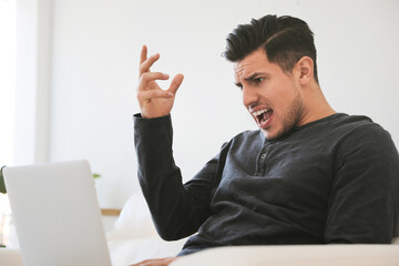 Emotional man working with laptop at home