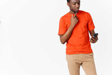 a guy in an orange T-shirt with a mobile phone on a Light background 