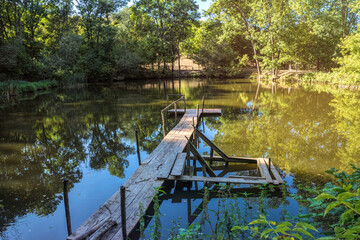 Summer forest lake and tarry wooden pier