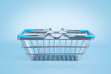 Supermarket shopping basket on light blue background. Empty metal wire basket. Black friday, sale,...