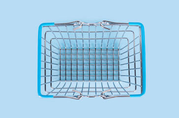 Top view of supermarket shopping basket on light blue background. Empty metal wire supermarket basket. Black friday, sale, shopping concept. Sustainable lifestyle
