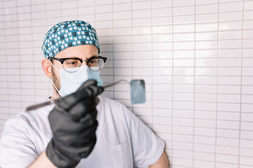 Young man doctor holding and looking at dental x-ray