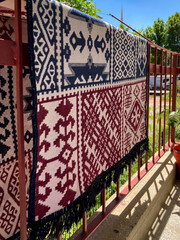 Close-up view of a traditional rug with authentic patterns hanging on the balcony railings. 