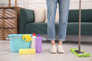 Woman washing floor with mop in living room, closeup