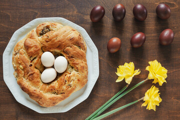 Savory cake in wreath shape. Traditional Easter stuffed baked bread and boiled eggs. Top view of Easter table.