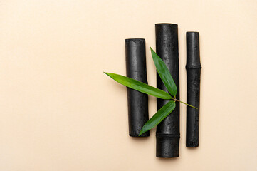 Bamboo activated charcoal sticks and green leaf on cream color  background.