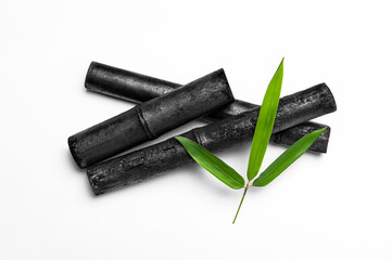 Bamboo activated charcoal sticks and green leaf isolated on white background.
