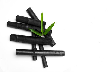 Bamboo activated charcoal sticks and green leaf isolated on white background.