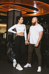 Portrait of a sports couple. Young trained woman and muscular guy. Trainer and ward in a sports club.