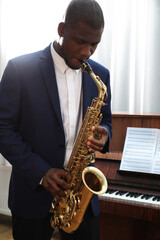 Fototapeta premium African-American man playing saxophone indoors. Talented musician