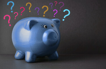 Blue piggy bank, with question marks on a black background. Concept of money, savings. Doubts about...