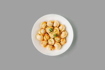Fried dumplings on white plate on gray.