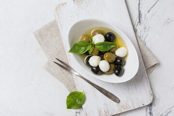 Bowl of delicious green and black olives with mozzarella in oil