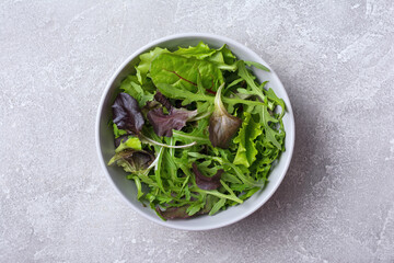 A bowl with mix of fresh green leaves for salad