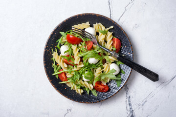 Pasta with cherry tomatoes, soft cheese and arugula leaves