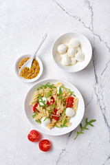 Pasta with cherry tomatoes, soft cheese, mustard sauce and arugula leaves