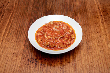 White plate with chunks of stewed meat in Spanish sauce