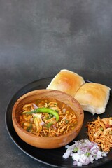 Spicy Misal Pav or usal Pav is a traditional snack or Chaat food from Maharashtra, India. Served with chopped onion, lemon wedges and farsan. Selective focus with copy space
