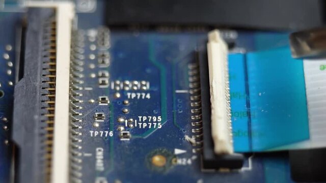 Connecting a flex cable to the laptop motherboard with tweezers, laptop repair in a service center