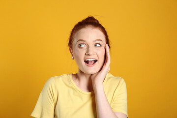 Portrait of emotional red haired woman on yellow background
