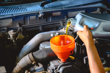 Car mechanic working in a car repair shop Pour the engine oil to change the engine oil in the...