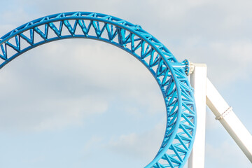 Loop and turn on blue color roller coaster in an amusement park. - obrazy, fototapety, plakaty
