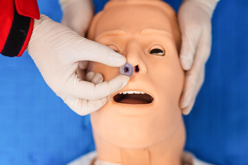 Top view of medical manipulation for airway management. Nasopharyngeal tube airway insertion by stuff in a black gloves on a simulation mannequin dummy during medical training. ACLS
