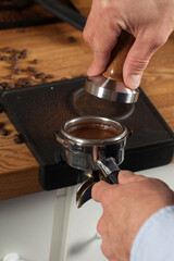 Barista pressing fresh coffee grounds in a cafe, selective focus