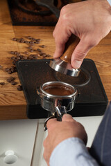 Barista pressing fresh coffee grounds in a cafe, selective focus