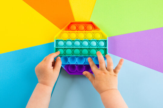 kids hands push sensory popit on colorfull background.