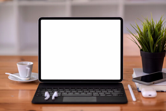 Mockup. Image of tablet white screen with keyboard smartphone coffee cup headphones on the office table.