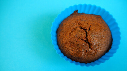 gluten-free chocolate muffin with apples in blue silicone mold stands on blue background top view, cooked at home