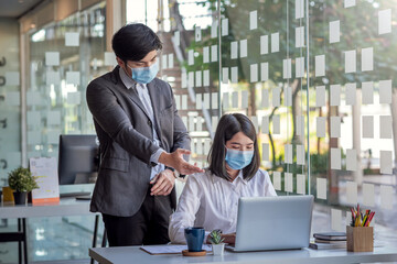 Asian Businessman and businesswoman consult to work together. Man manager working at the office concept . Wear a mask.