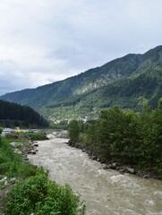 A picture of the beautiful Beas river flowing through the Himalayan mountains in Manali, cutting through forests and rocks.