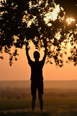 Portrait young man praying hands up against sunset