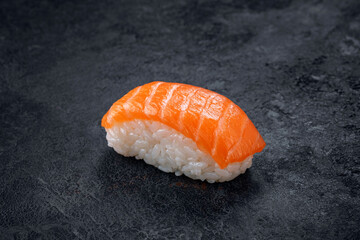 One nigiri sushi with salmon on a stone dark background. Japanese dish sushi of fresh fish