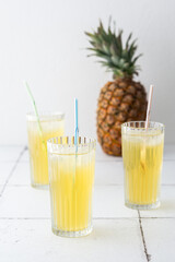 Delicious sweet refreshing pineapple juice with ice in glasses with a straw