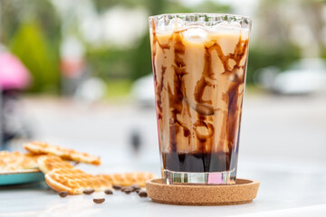 Iced caramel latte coffee in a tall glass with caramel syrup